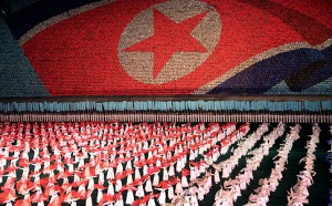 North Korean women dance in front of a display of their country's national flag on Monday, July 22, 2013 in Pyongyang, North Korea. North Korea has revealed a new rendition of the "Arirang" mass games, the song-and-dance ensemble. This year’s performance was timed to debut for the 60th anniversary Saturday of the end of the Korean War, and features new scenes focusing on leader Kim Jong Un’s directives. (AP Photo/Wong Maye-E)